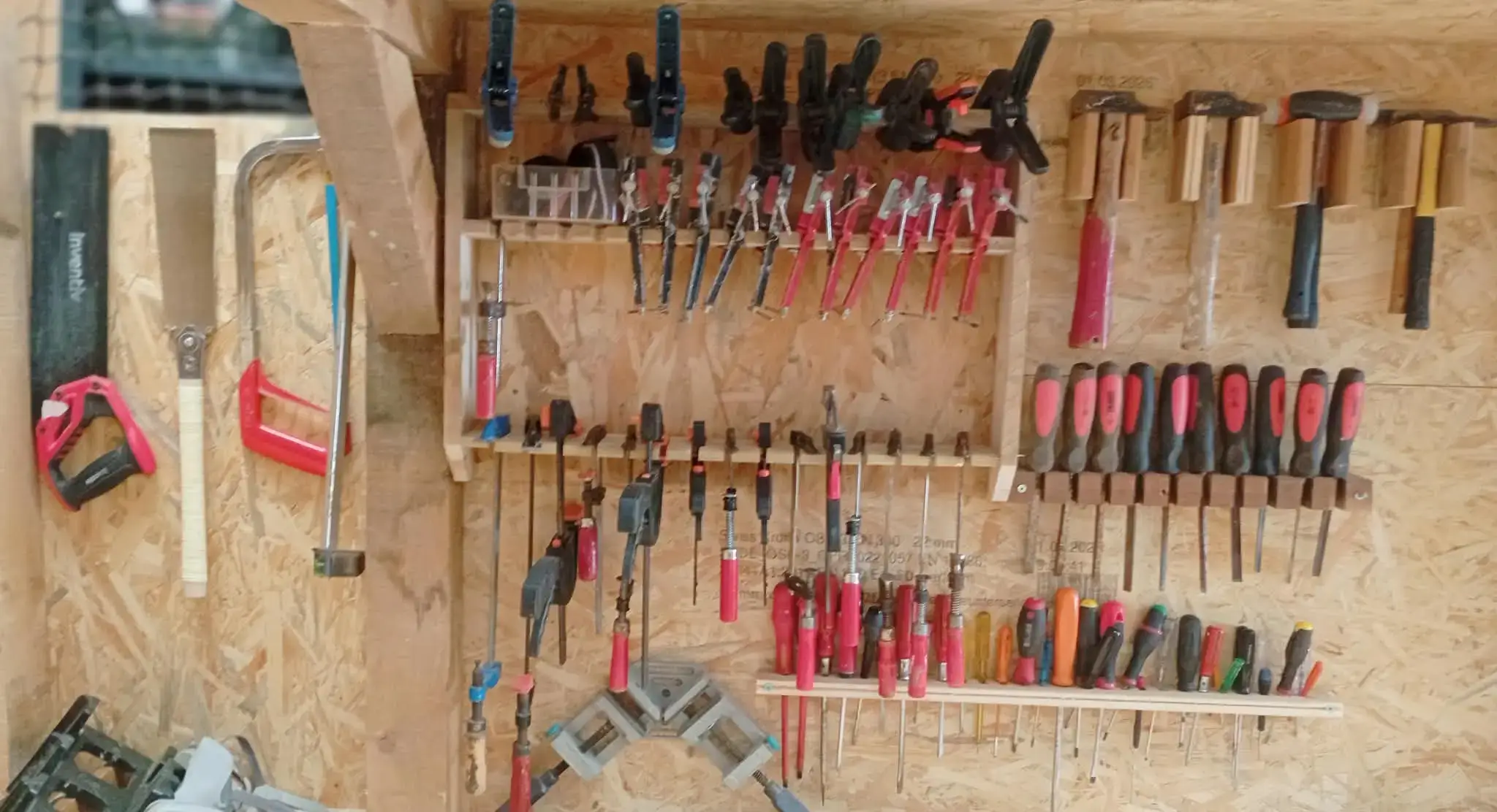 Le mur d'outils de l'atelier : serre-joints, marteaux, tournevis et limes
